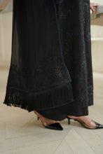 تصویر گیلری ویور میں لوڈ کریں، A close-up of a black sheer embroidered dress with fringe and lace detailing on dupatta worn by a model in clear-strap pointed-toe heels on a light beige tiled floor.
