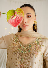 Load image into Gallery viewer, Woman wearing a beige embroidered traditional outfit with gold jewelry, holding a pink and green leaf.