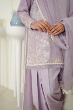 تصویر گیلری ویور میں لوڈ کریں، A close-up of a person wearing a lavender traditional outfit with white floral embroidery and lace trim, standing indoors near a white pedestal.
