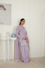 تصویر گیلری ویور میں لوڈ کریں، A woman models a lavender purple traditional outfit with matching pants and a draped scarf featuring white embroidery, standing in a bright, minimalist room with white paneled walls and decorative side tables.
