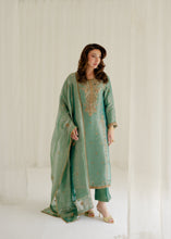 Load image into Gallery viewer, Woman wearing a green traditional outfit with embroidery in a white room.
