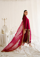 Load image into Gallery viewer, Woman in a red and gold traditional outfit standing in a softly lit room with white curtains.
