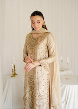 Load image into Gallery viewer, Woman wearing a beige embroidered traditional outfit in a softly lit room.
